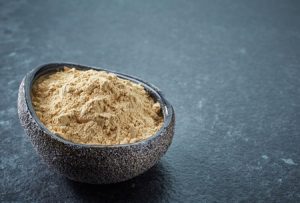 Bowl of healthy maca powder on dark background