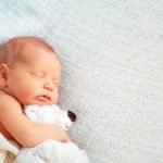 51236159 - cute newborn baby sleeps with a toy teddy bear white