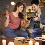 Red wine being drunk by a loving couple at a table with sushi in a nice hotel.