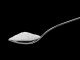 Spoon full of sugar isolated on black background. Can be replaced with sucralose.
