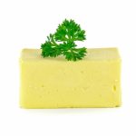 A bar of butter with a parsley leaf on top, on a white background.