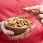 Woman eating healthy snack of almonds
