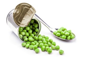 Opened tin with green peas on spoon. Isolated on white background
