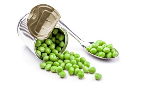 Opened tin with green peas on spoon. Isolated on white background