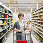 Pretty woman with a cart shopping and choosing goods at the supermarket. Healthy food.