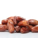 Photograph of sugar covered and dried dates (deglet noor sub-type) palm fruits on white with a natural reflection. the fruit is also known as phoenix dactylifera.