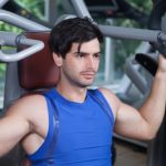 Man in blue vest doing shoulder press.