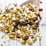 Mixed pulses in a wooden spoon on a wooden table.. An example of pulse ingredients which can be turned into all sorts of foods.