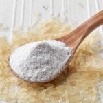 Spoon of rice flour on white wooden background