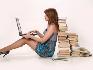 Girl with a laptop next to a pile of books. She may take huperzine.