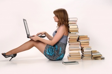 Girl with a laptop next to a pile of books. She may take huperzine.