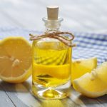 Lemon oil in a glass bottle with fresh lemon on wooden background