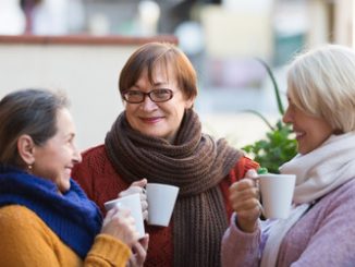 Portrait of smiling senior female friends drinking coffee at patio