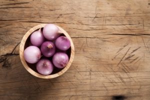 Shallots in a bowl on a wooden table.