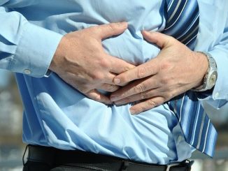 Man gripping his stomach. Could have stomach ulcers or other digestive issues.
