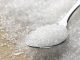 Close-up of granulated sugar in spoon and sugar pile.