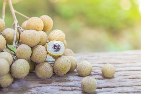 Fresh ripe longan fruits and leaves on a wooden board