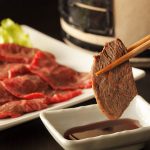 Yakiniku japanese barbecue, chopsticks picking up slices of beef.