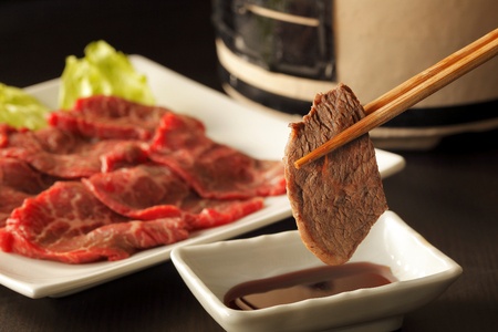 Yakiniku japanese barbecue, chopsticks picking up slices of beef.