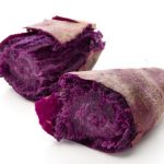 Purple ube, a yam cut in half on a white background.