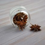 Star anise in a jar on a grey table.