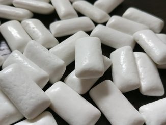 Chewing gum, white and in near focus on a black background.