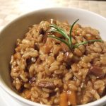 Brown rice risotto in a white bowl.