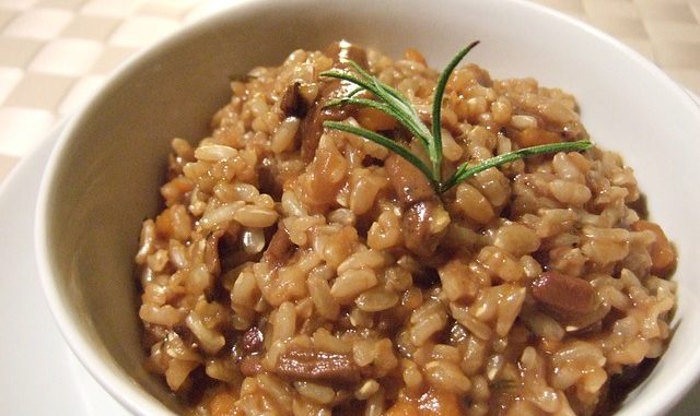 Brown rice risotto in a white bowl.
