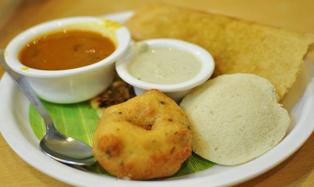 South Indian breakfast with a vada doughnut. at the front, idli and chutney.