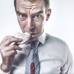 man eating a sweet snack in a shirt and tie. sugar tax.