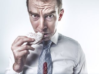 man eating a sweet snack in a shirt and tie. sugar tax.