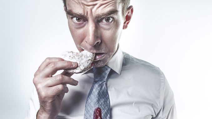 man eating a sweet snack in a shirt and tie. sugar tax.