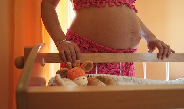 Pregnant women leaning on a crib. Increase chance of conception.