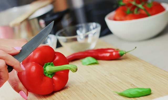 Red pepper being cut with a knife by a goblin.