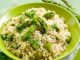 A risotto with asparagus in a pale green bowl on a green cloth with asparagus.