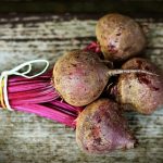 Beets tied up with string and lying on a grey brown wooden table