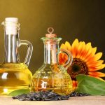 Sunflower oil and sunflower on yellow background. An example which contains PUFAs.