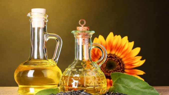 Sunflower oil and sunflower on yellow background. An example which contains PUFAs.