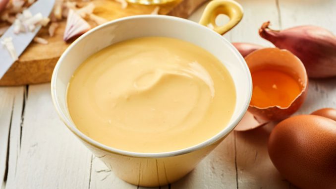 Hollandaise sauce. Bowl of gourmet creamy Hollandaise sauce made with egg yolks, butter, lemon juice and vinegar blended together in a close up view