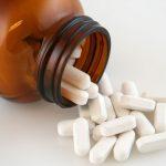 White calcium pills pouring out of bottle. calcium supplements are an important OTC product.