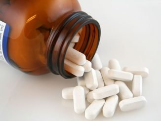 White calcium pills pouring out of bottle. calcium supplements are an important OTC product.