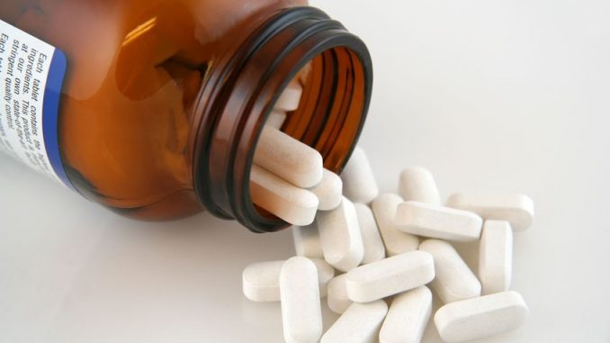 White calcium pills pouring out of bottle. calcium supplements are an important OTC product.