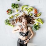 Beauty portrait of a sports woman surrounded by various healthy food lying on the floor. Healthy eating and exercise concept. Top diets 2019