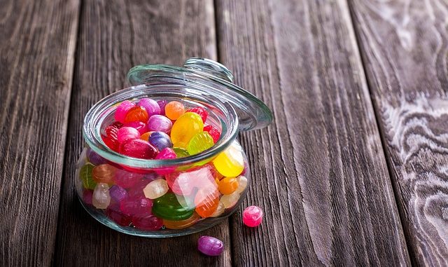 Sweets or candy in a jar on a wooden table.Junk food.
