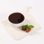 bowl of date syrup with dates on white table mat