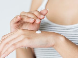 Cosmetics and personal care creams containing carbomer and menthoxypropanediol being applied to back of hand.