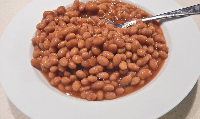 Boston-baked-beans in a white dish with spoon. Prepared with a slow cooker or multi-function cooker.