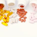 Pills, tablets, all containing dietary supplements in whiite pots on a white background.