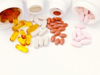 Pills, tablets, all containing dietary supplements in whiite pots on a white background.