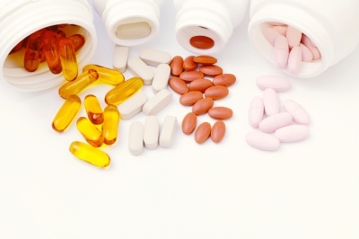 Pills, tablets, all containing dietary supplements in whiite pots on a white background.